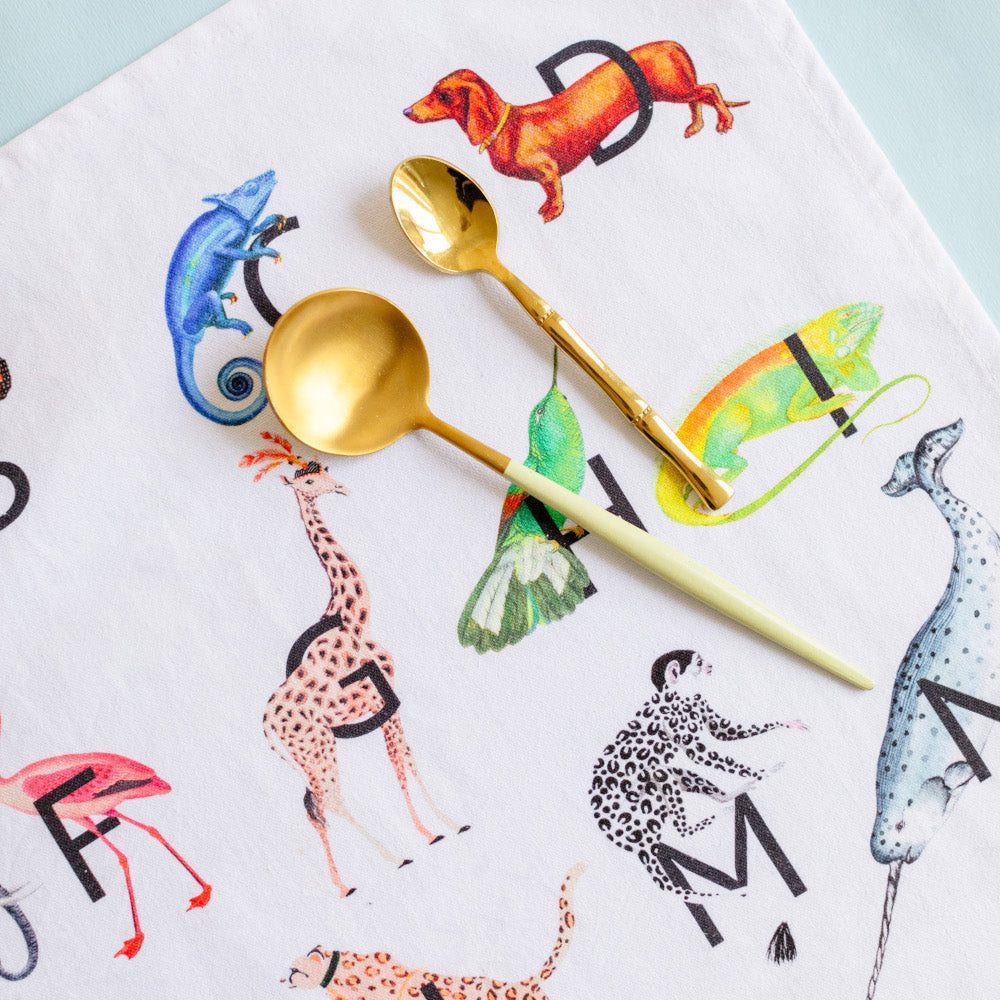 Close up of gold spoons on Alphabet tea towel