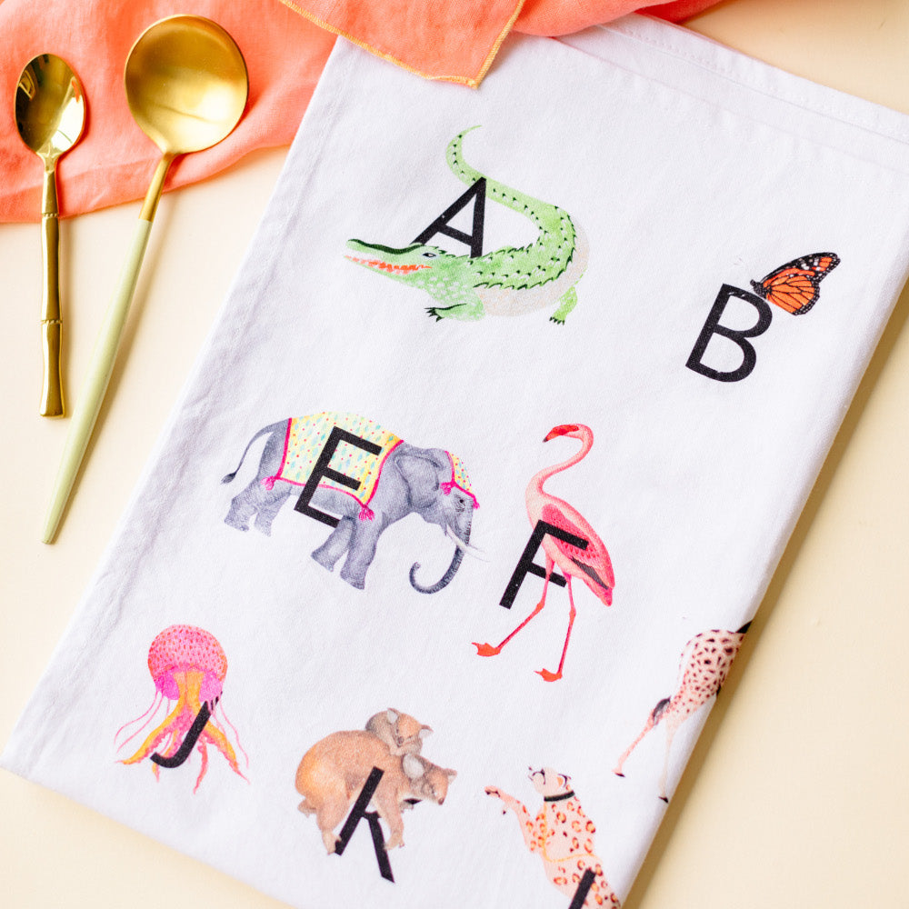 Alphabet tea towel with gold spoons at the side